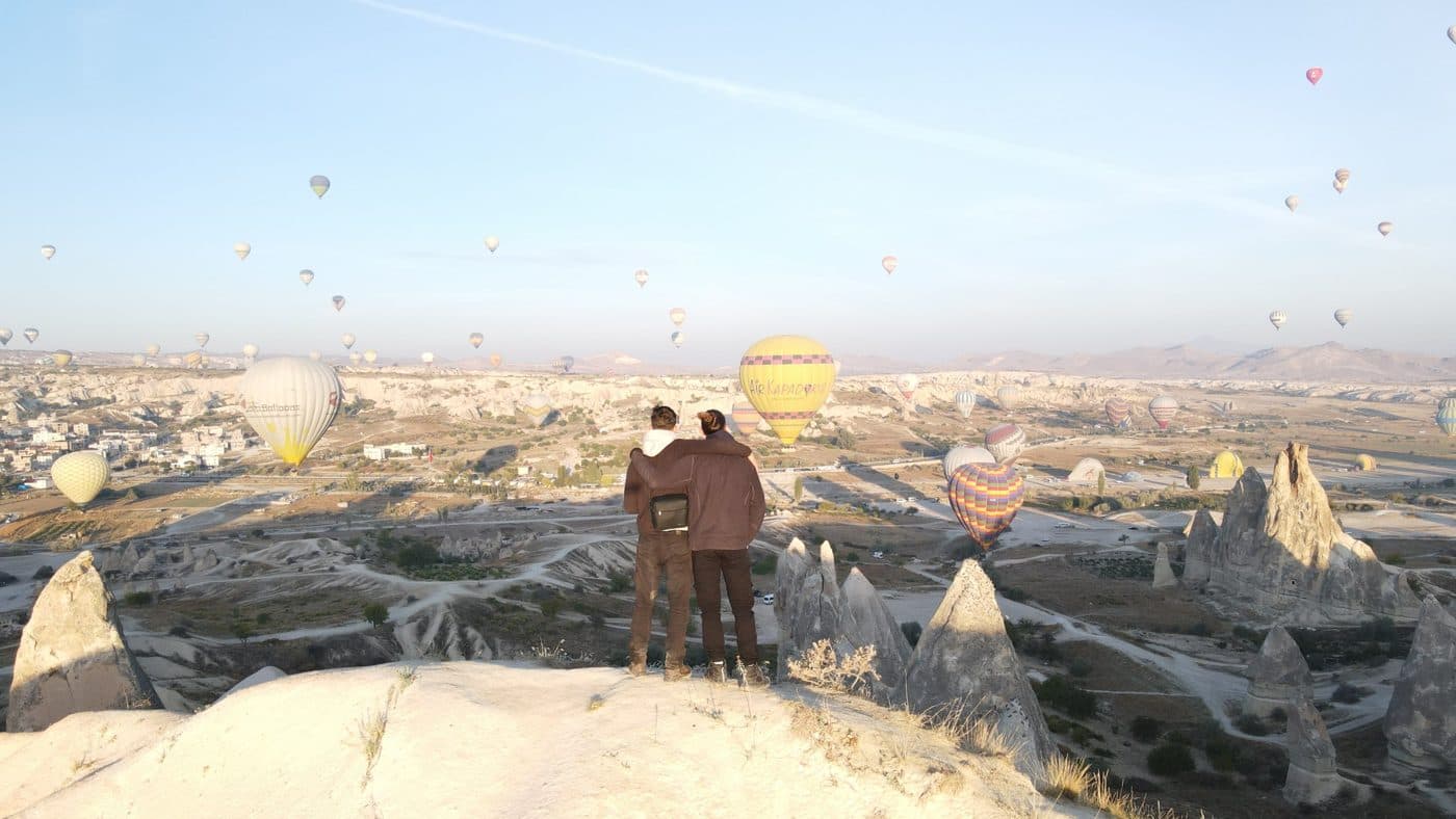 Deux voyageurs face aux montgolfières de Cappadoce