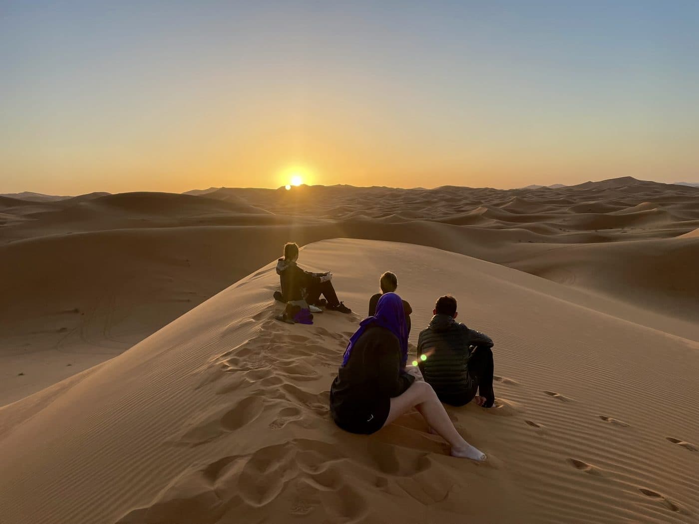 Le groupe assis sur une dune face au coucher du soleil