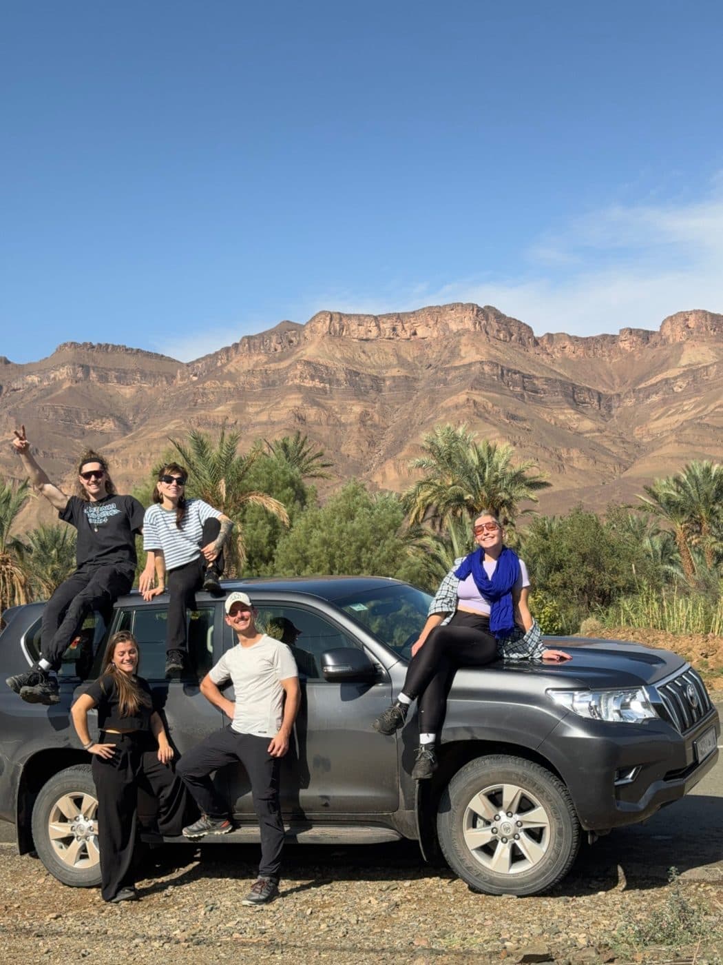 Le groupe sur un 4x4 devant les montagnes et la palmeraie