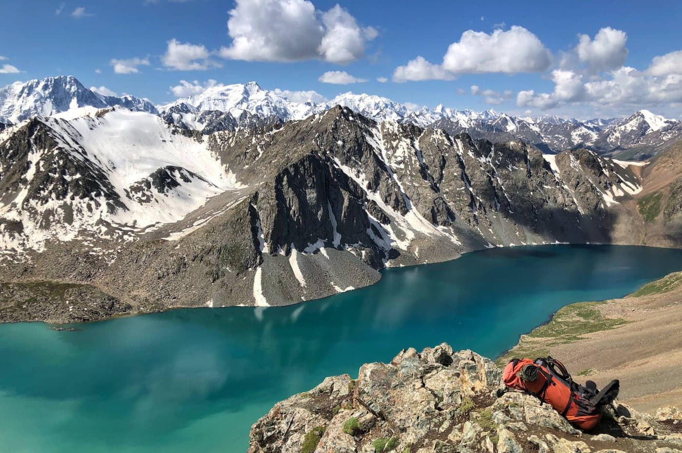 Sac à dos face au lac Ala-Köl et aux sommets enneigés